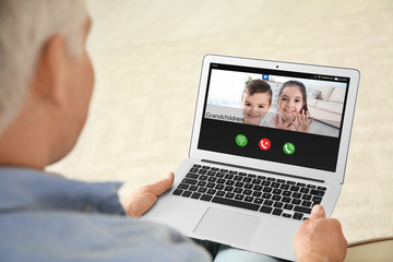 Closeup view of senior man talking with grandchildren via video chat at home - obrazy, fototapety, plakaty