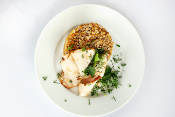 Chicken breast, buckwheat salad with greens on a white plate.