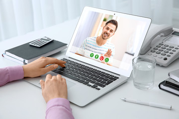 Fototapeta premium Woman using laptop for conversation with man via video chat at table, closeup