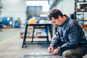 Man controlling metal parts with a caliper measuring device.