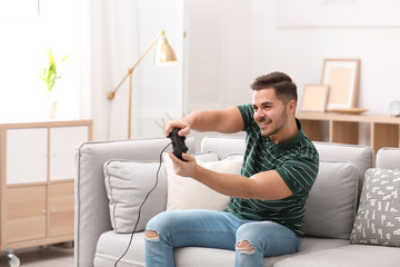 Emotional young man playing video games at home © New Africa