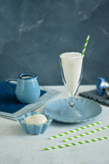 Ice cream milkshake in a glass glass. Ice cream balls in a blue ceramic cream bowl. Light blue background. Summer brunch. 
