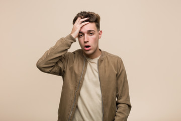 Young caucasian man wearing a brown jacket tired and very sleepy keeping hand on his head.