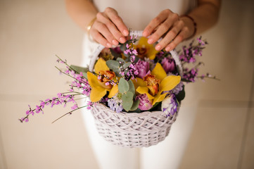 Close shot of woman holding small basket with flowers