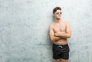 Young caucasian man wearing swimsuit smiling confident with crossed arms. © Asier