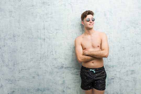 Young caucasian man wearing swimsuit smiling confident with crossed arms.