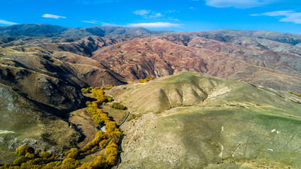 Hill terrain with small rivers and valleys on a sunny day. Otago, South Island, New Zealand