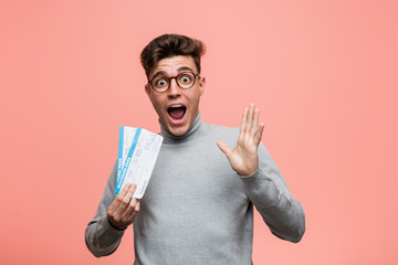 Young cool man holding an air tickets celebrating a victory or success