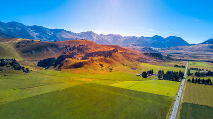 Road running through farmland with mountains on the background. West Coast, South Island, New...
