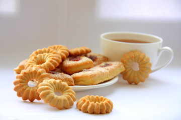 White cup with tea and biscuits.