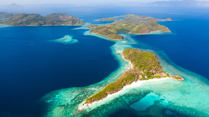An island with a sandy beach and a coral reef.Philippine islands with white beaches aerial view