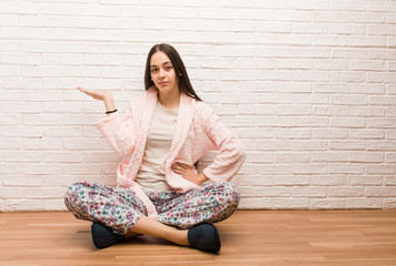 Young woman wearing pajama holding something with hand
