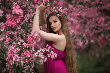 Beautiful girl in blossom apple garden with pink flowers, spring time