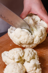 young woman in a gray aprons cuts cauliflower broccoli