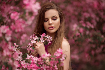 Naklejka premium Beautiful girl in blossom apple garden with pink flowers, spring time