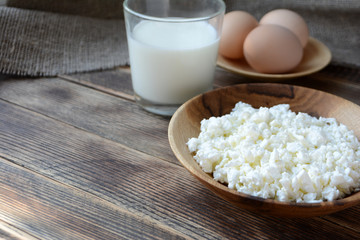 Cottage cheese in a wooden bowl, milk in a glass, eggs. Farm products. Village Breakfast