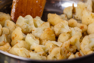 young woman in a gray apron roasts cauliflower broccoli