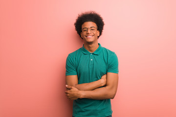 Young african american man over a pink wall crossing arms, smiling and relaxed