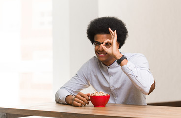 Fototapeta na wymiar Young black man having a breakfast confident doing ok gesture on eye