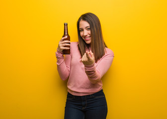 Young cute woman holding a beer inviting to come