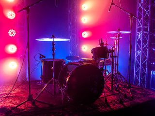 Fototapeta na wymiar Drum set on the stage of a concert hall or club in a beautiful bright light. Drum set at a rock concert
