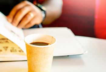 A mug of coffee with a black man reading a book