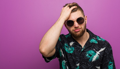 Young man wearing a vacation look tired and very sleepy keeping hand on his head.