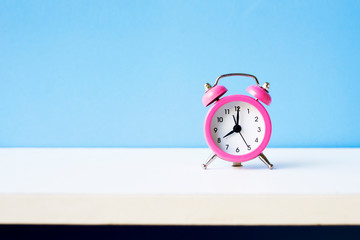 Pink alarm clock on blue pastel background with coppy space