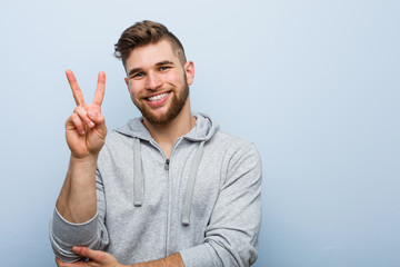 Young handsome fitness man showing number two with fingers.