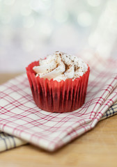 Red velvet cupcake on decorative plaid cloth with a shallow depth of field