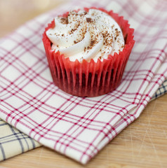 Red velvet cupcake on decorative plaid cloth with a shallow depth of field