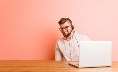 Young man working in a call center looks aside smiling, cheerful and pleasant.