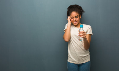 Young black woman covering ears with hands. She is holding a water bottle.