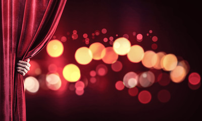 Bokeh lights behind drapery curtain and hand opening it