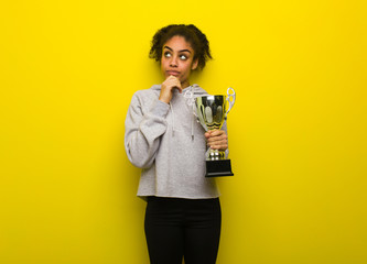 Young fitness black woman thinking about an idea. Holding a trophy.