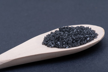 Fototapeta na wymiar Hawaiian Black Lava Sea Salt in handmade wooden spoon on dark background.