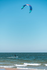 Wide shot of kitesurfer swimming on an ocean or sea near beach. Summer color grading. Vertical orientation. 