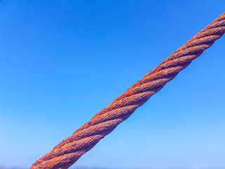 oxidized interlocked wire loop cables in the foreground with sky and sea bottoms. Image taken in...