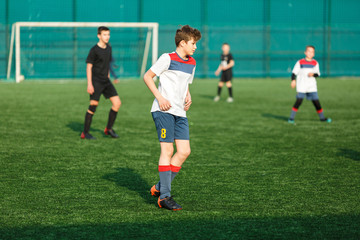 Football teams boys in yellow white sportswear play soccer on the green field. Dribbling skills.