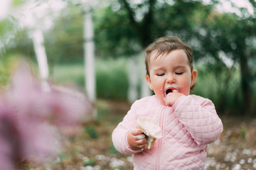 little girl in the garden on the background of greenery and trees very cute eating ice cream in a waffle Cup