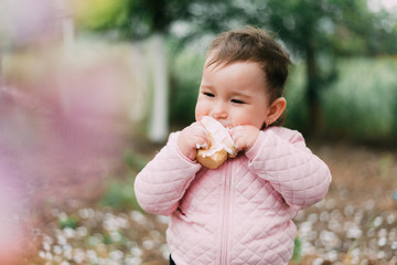 little girl in the garden on the background of greenery and trees very cute eating ice cream in a waffle Cup