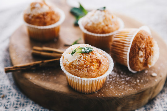 Home-baked muffins with cinnamon and mint on wooden board
