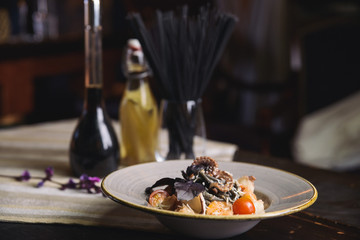 Fototapeta na wymiar black spaghetti with octopus, shrimp, cherry tomatoes and basil