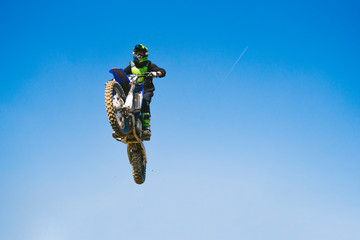 Motocross driver jumping in blue sky