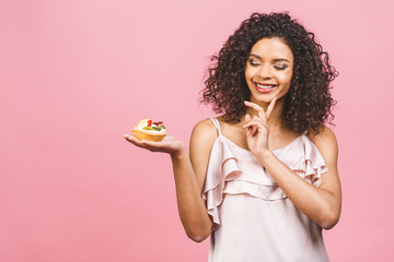 Black american african happy woman with curly afro hair style making a mess eating a huge fancy...