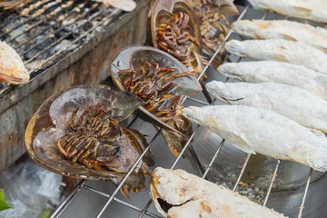 Salt-Crusted Grilled Seabass fish grill on charcoal stove for sale at Thai street food