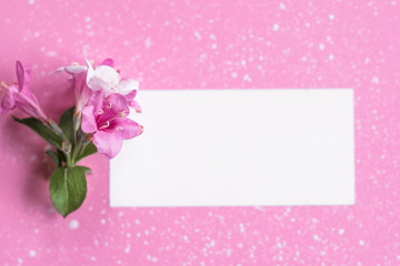 Styled feminine flat lay on pale pastel pink background, top view. Minimal woman's desktop with blank page mock up, open envelope and pink flower, Creative concept, empty greeting card 
