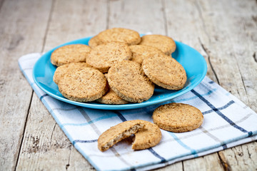 Fresh baked oat cookies on blue ceramic plate on linen napkin on rustic wooden table.