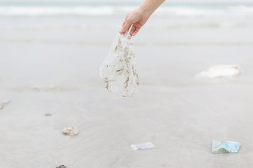 Hand woman picking up plastic bag cleaning on the beach