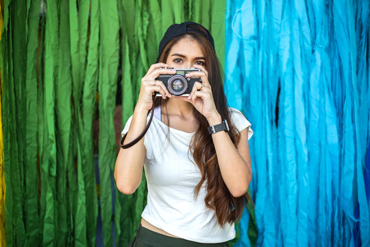 young beautiful woman holding retro film camera to take photograph while travel in the city street